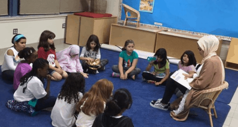 Teacher reading to children seated in circle.