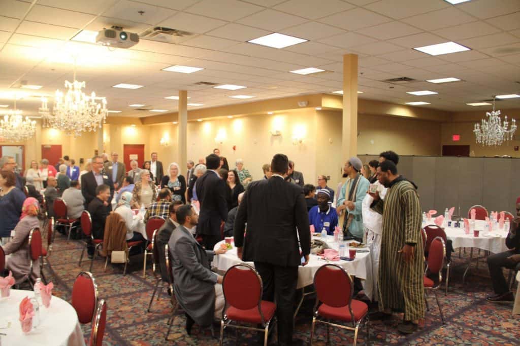 A group of people standing around tables in a room.